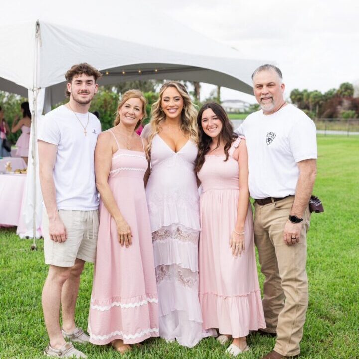 Group portrait by tent, women in pink dresses