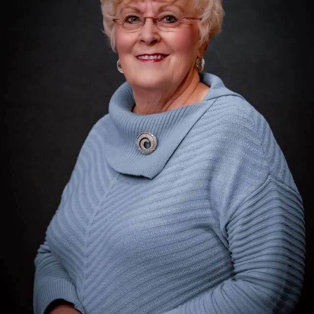 Smiling older woman with glasses, blue sweater